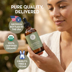 Woman holding a bottle of organic jojoba oil with text highlighting USA-grown, certified organic, cruelty-free, and vegan benefits.