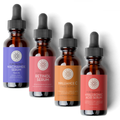 Four bottles of skincare serums with droppers on a white background