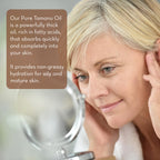 A person with light hair looking into a mirror, applying skincare product to their face. The text overlay describes the benefits of Cold Pressed Tamanu Oil, highlighting its rich fatty acids, quick absorption, and non-greasy hydration suitable for oily and mature skin.