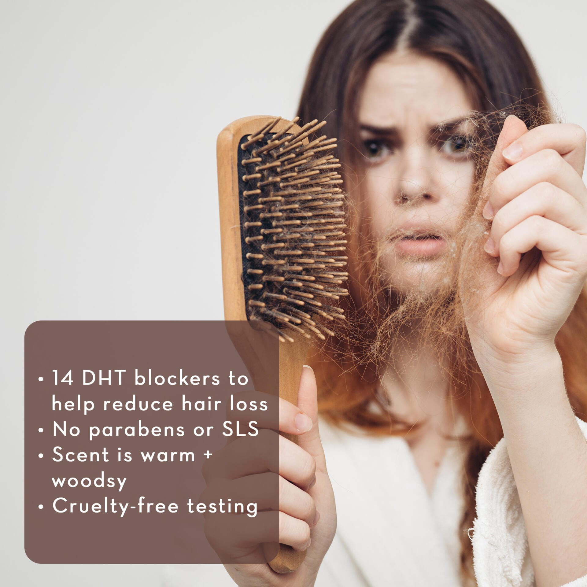 A worried woman with long hair looks at a hairbrush filled with hair. A text overlay lists product features: 14 DHT blockers to help reduce hair loss, no parabens or SLS, warm and woodsy scent, cruelty-free testing. She is dressed in a white robe. The product, Restore & Strengthen Shampoo for Hair Growth, appears prominently beside her.