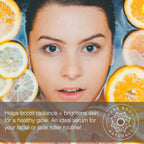 Close-up of a person's face partially submerged in water with orange and lemon slices around them. The text overlay reads: "Helps boost radiance + brightens skin for a healthy glow. An ideal serum for your facial or jade roller routine!" The Brilliance-C Vitamin C Face Serum logo is present.