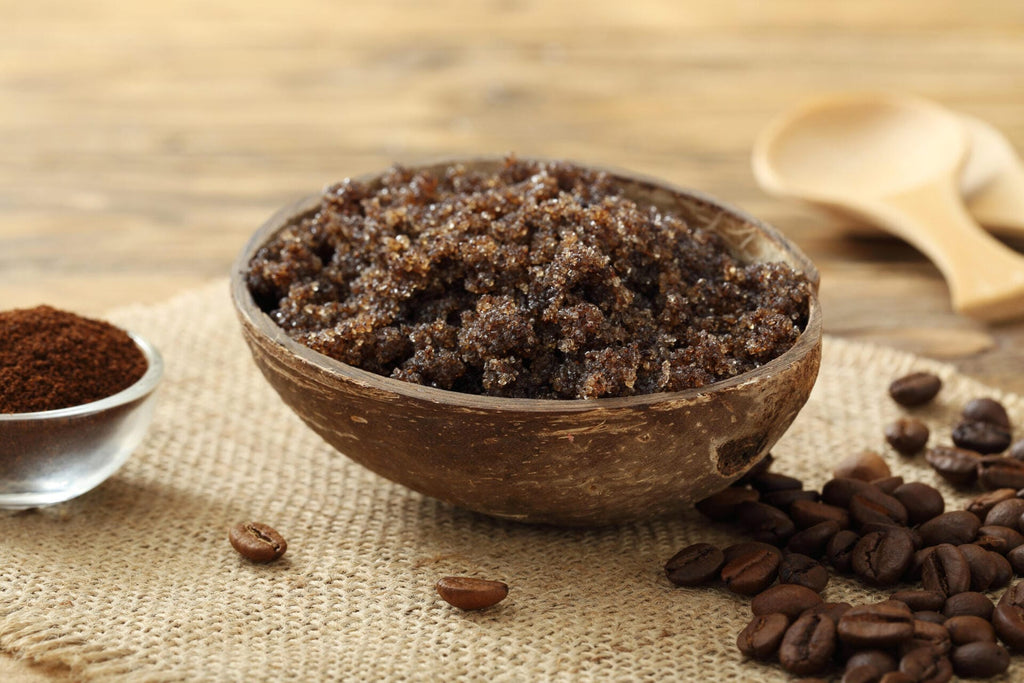 Wooden bowl filled with coffee scrub on a wooden surface with coffee beans around