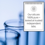 The image shows a Peppermint Essential Oil, 4 fl oz with the logo "Pure Body Naturals" and the text "Our oils are 100% pure + tested at trusted independent labs." In the background, out-of-focus glass test tubes are visible. The overall color scheme is blue and white.