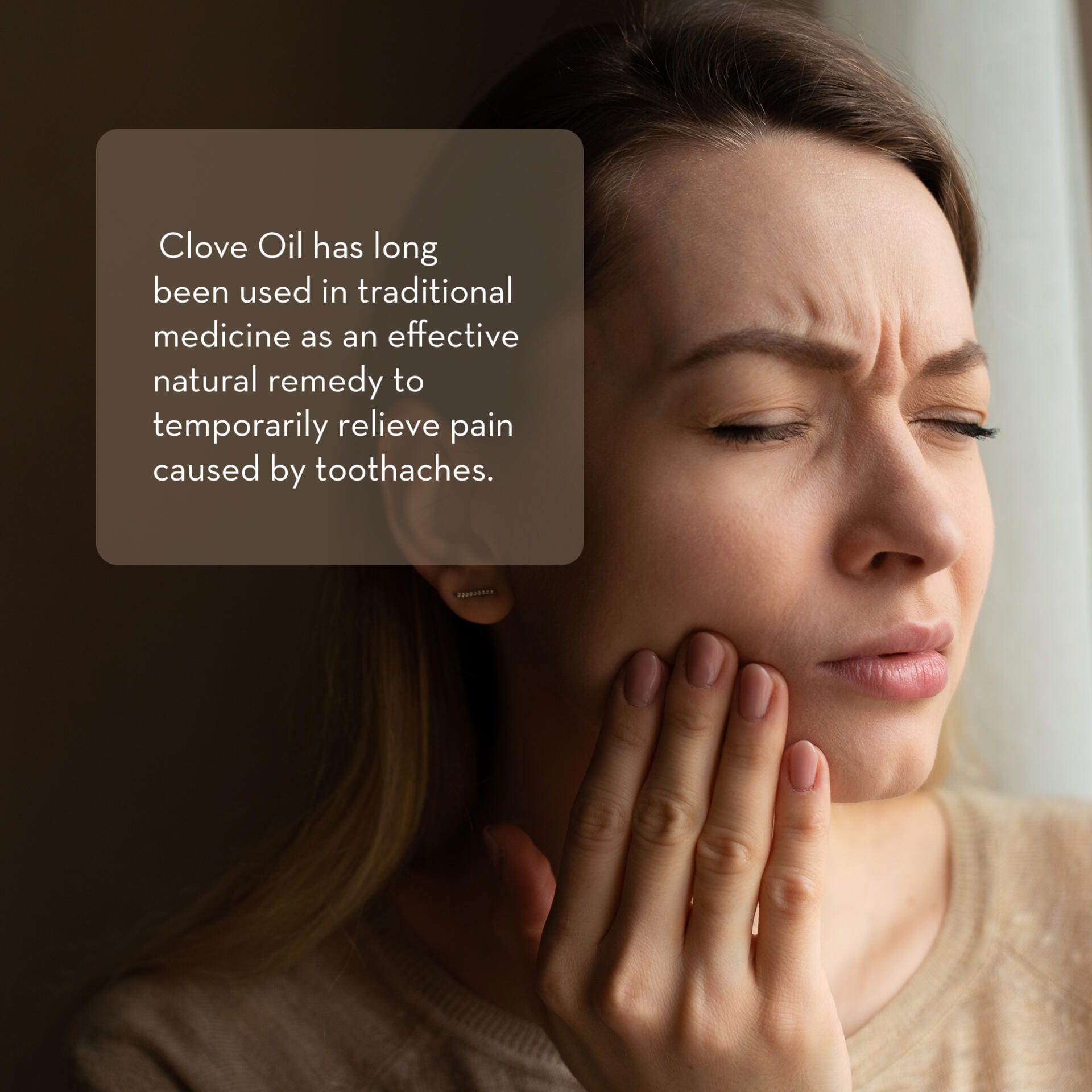A woman with a pained expression holds her hand to her cheek, indicating a toothache. A text overlay reads, "Clove Essential Oil, 10 ml has long been used in traditional medicine as an effective natural remedy to temporarily relieve pain caused by toothaches.