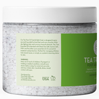 A clear plastic jar filled with bath salts is shown. The label reads "Epsom Salt Foot Soak with Tea Tree Oil." The product is distributed by Pure Body Naturals and made in the USA. Lyrics and warnings caution against use near children and advise consulting a doctor if pregnant.