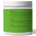 A white plastic jar with a green label lists the ingredients and directions for use of Tea Tree Oil Body and Foot Scrub. Ingredients include various essential oils and salts. Directions advise massaging onto wet skin and rinsing. It also includes a warning to keep out of reach of children.