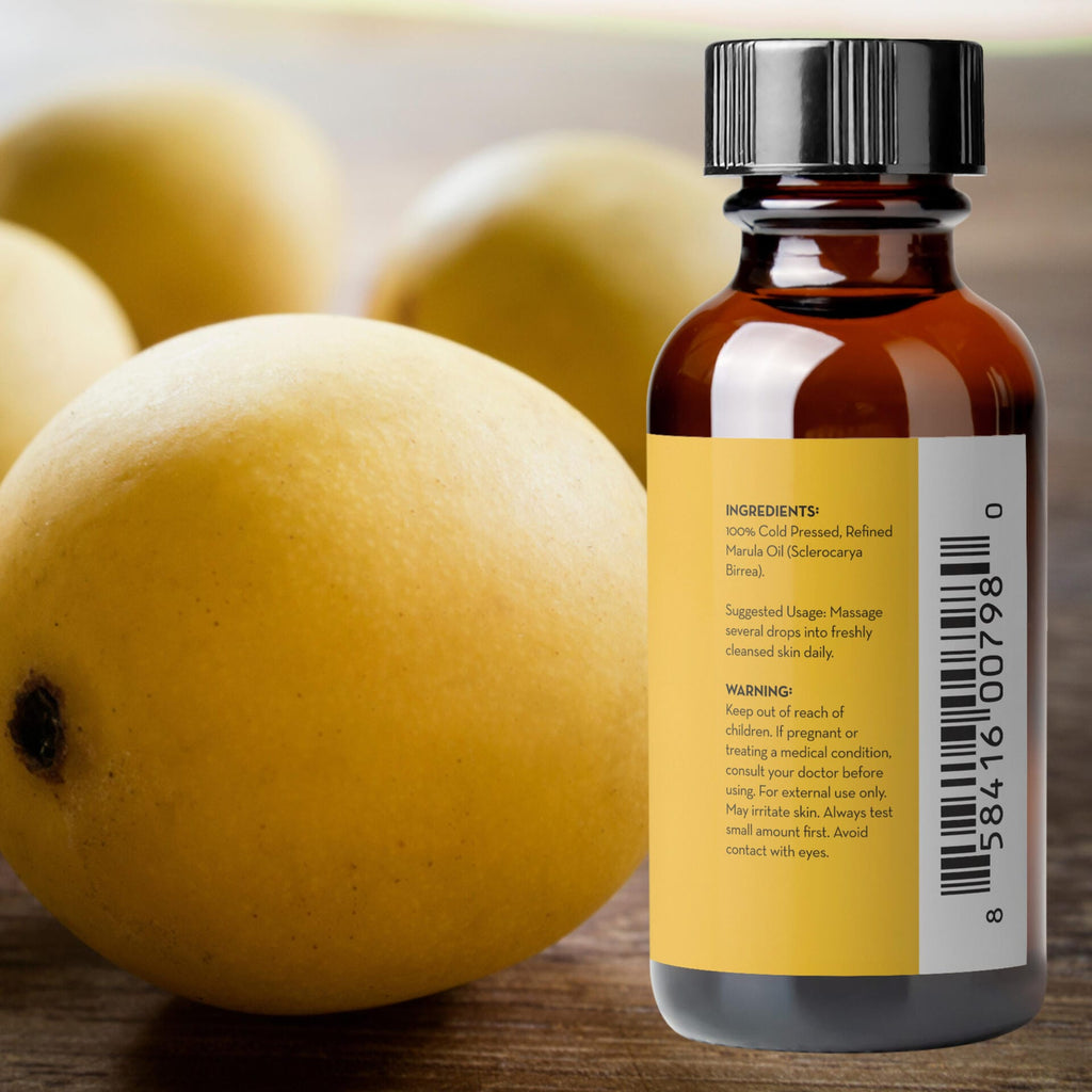 Bottle of oil with a label in front of mangoes on a wooden surface