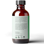 A dark amber bottle with a black cap stands on a white background. The label on the bottle is green and contains a detailed description of the product, Fractionated Coconut Oil, 100% Pure, and its benefits. Various certification logos are displayed at the bottom.