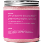 A pink jar labeled with ingredient and caution information. Ingredients listed include Himalayan salt, sweet almond oil, glycerin, grape seed oil, jojoba seed oil, vitamin E, aloe vera leaf juice, and fragrance oil. The caution advises keeping out of reach of children. Product Name: Himalayan Pink Salt Exfoliating Scrub.
