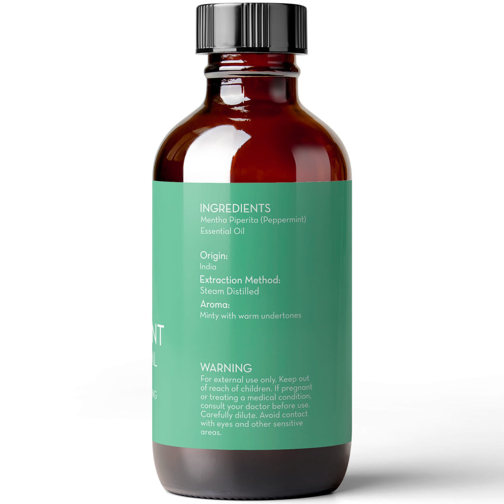 A brown glass bottle with a black cap and a green label. The label includes text listing ingredients, origin (India), extraction method (steam distilled), aroma (minty with warm undertones), and warnings about external use and keeping out of reach of children. Product Name: Peppermint Essential Oil, 4 fl oz