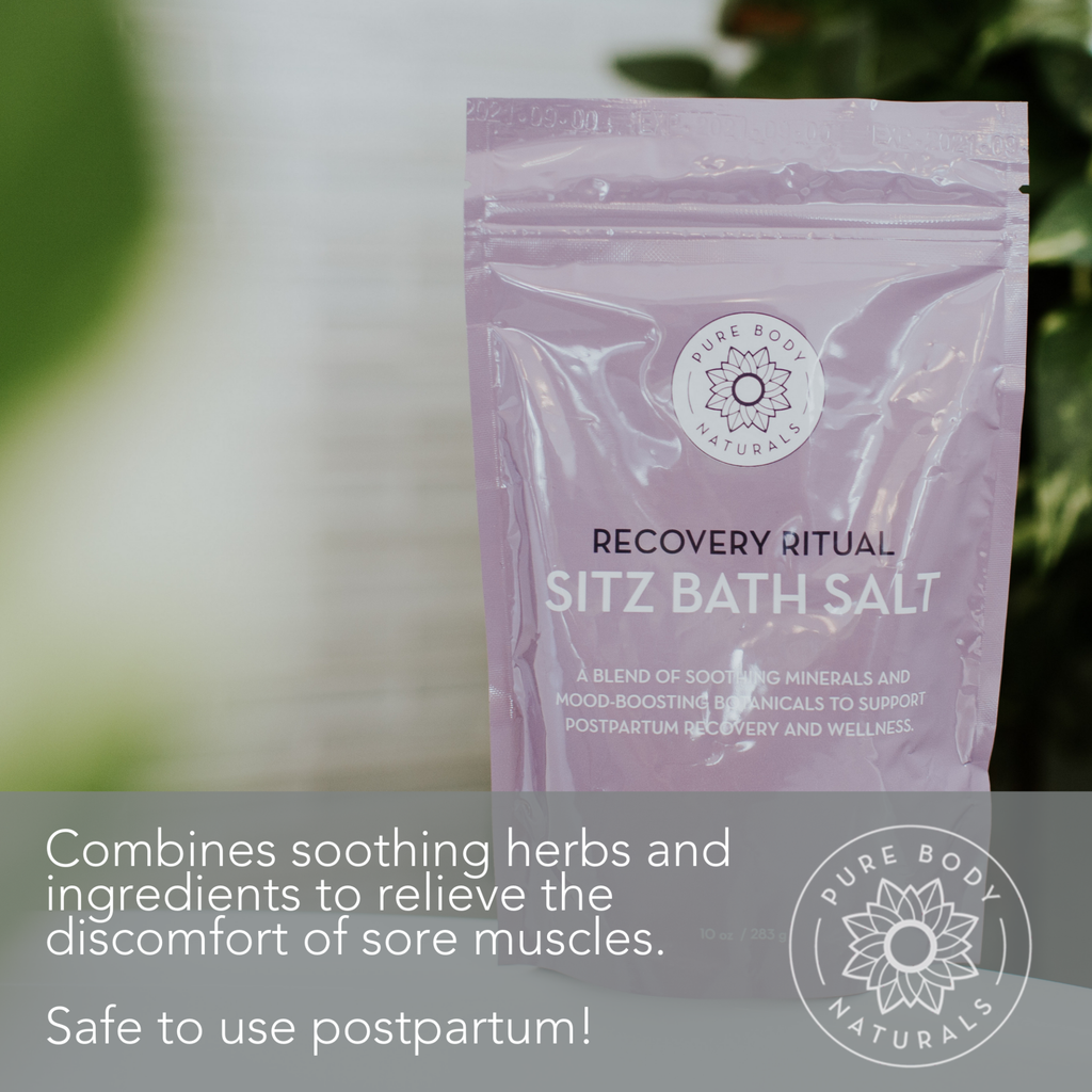 A lavender-colored package of Recovery Ritual Sitz Bath Salt, 10 oz is placed on a surface, with the brand logo and description that it combines soothing herbs and ingredients to relieve sore muscles and is safe for postpartum use.