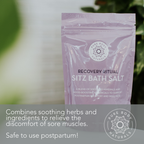A lavender-colored package of Recovery Ritual Sitz Bath Salt, 10 oz is placed on a surface, with the brand logo and description that it combines soothing herbs and ingredients to relieve sore muscles and is safe for postpartum use.